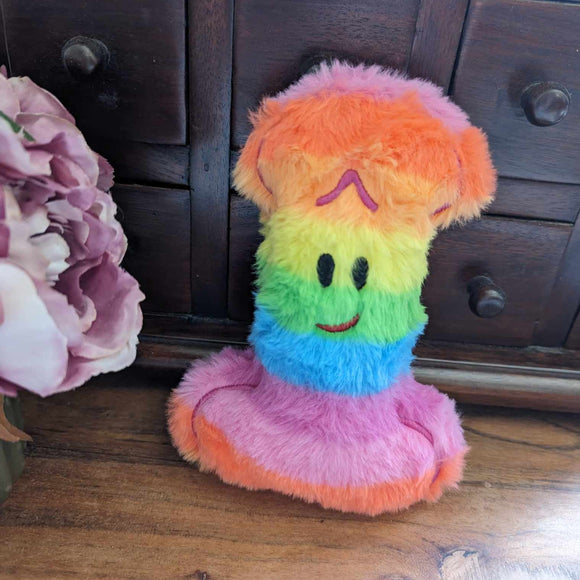 Plush Penis toy made from bright rainbow coloured faux fur fabric with a happy smiling face.