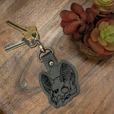 Close‑up of embroidered bat skull on grey faux leather keyring