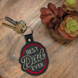 Close‑up of embroidered Best Dad Ever keychain in black and red