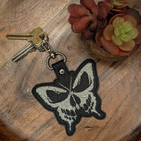 Close‑up of embroidered butterfly skull keychain in black and white