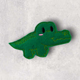 Green handmade crocodile finger puppet displayed flatlay on marble background.