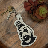 Close‑up of embroidered cult horror inspired clown keychain with bold black and white design
