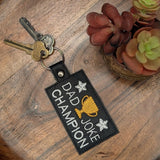 Close‑up of embroidered Dad Joke Champion keychain with trophy design
