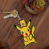 Close‑up of embroidered yellow mouse creature keychain with red cheeks