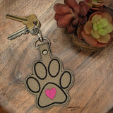 Close‑up of embroidered paw print keychain with pink heart