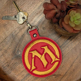 Close‑up of embroidered red emblem keychain with yellow border