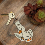 Close‑up of embroidered Murder Bird keychain in black and white on faux leather