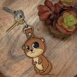 Close‑up of embroidered otter keychain with tan belly