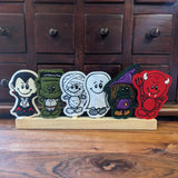 Embroidered felt finger puppets in Halloween designs; Dracula, Frankenstein, mummy, ghost, witch and devil sitting on a wooden display stand.