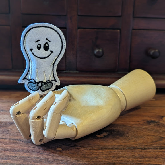 Embroidered ghost halloween finger puppet made from felt displayed on a wooden mannequin hand. 