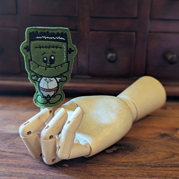 Embroidered Dracula halloween finger puppet made from felt displayed on a wooden mannequin hand. 