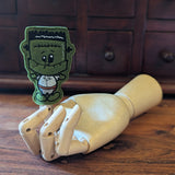 Embroidered Dracula halloween finger puppet made from felt displayed on a wooden mannequin hand. 