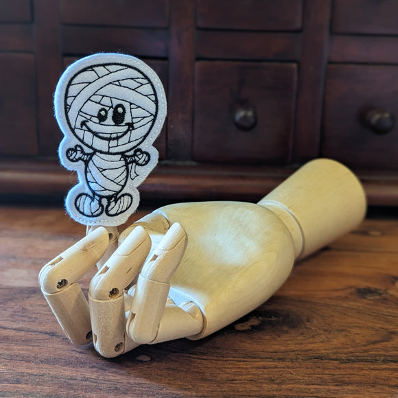Embroidered Egyptian Mummy halloween finger puppet made from felt displayed on a wooden mannequin hand. 