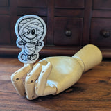 Embroidered mummy halloween finger puppet made from felt displayed on a wooden mannequin hand. 