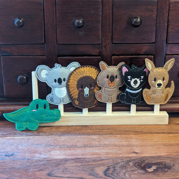 Embroidered felt finger puppet set in native Australian animal designs; koala, echidna, wombat, tasmanian devil, kangaroo and crocodile sitting on a wooden display stand.