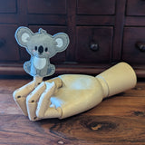Embroidered koala finger puppet made from felt displayed on a wooden mannequin hand. 