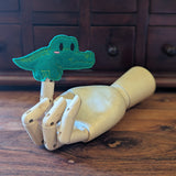 Embroidered crocodile finger puppet made from felt displayed on a wooden mannequin hand. 