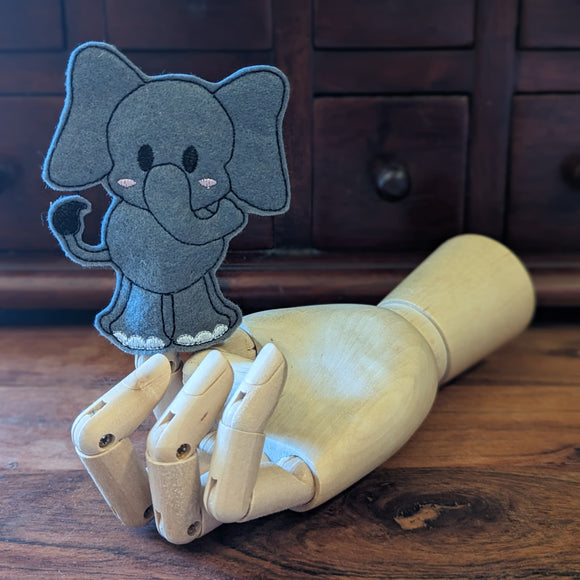 Embroidered elephant finger puppet made from felt displayed on a wooden mannequin hand. 