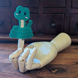 Embroidered snake finger puppet made from felt displayed on a wooden mannequin hand. 