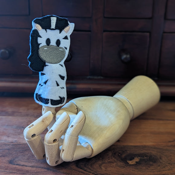 Embroidered zebra finger puppet made from felt displayed on a wooden mannequin hand. 