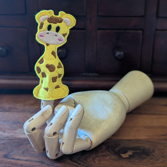 Embroidered giraffe finger puppet made from felt displayed on a wooden mannequin hand. 