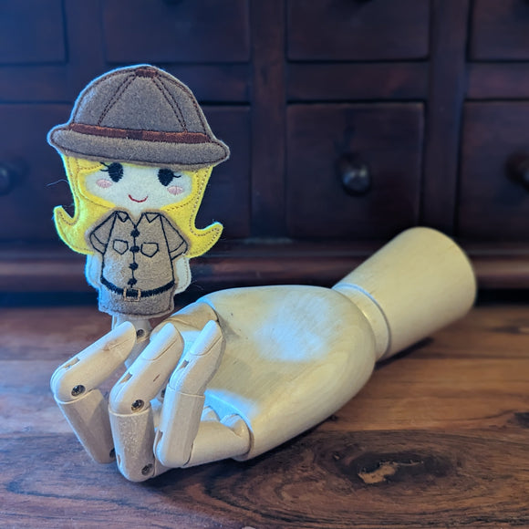 Embroidered female safari guide finger puppet made from felt displayed on a wooden mannequin hand. 