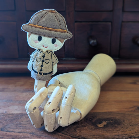 Embroidered male safari guide finger puppet made from felt displayed on a wooden mannequin hand. 