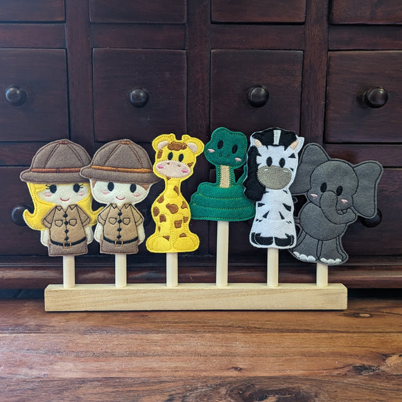 Embroidered felt finger puppet set in cute safari designs; two safari guides, giraffe,snake, zebra and elephant sitting on a wooden display stand.