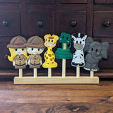 Embroidered felt finger puppet set in cute safari designs; two safari guides, giraffe,snake, zebra and elephant sitting on a wooden display stand.