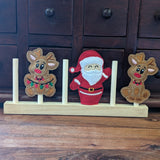 Embroidered felt finger puppets in cute Christmas designs; Santa and two different reindeers sitting on a wooden display stand.