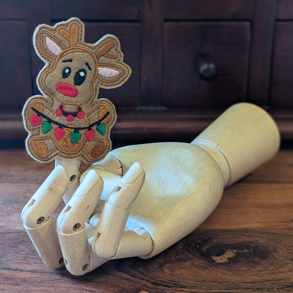Embroidered Rudolph finger puppet made from felt displayed on a wooden mannequin hand. 