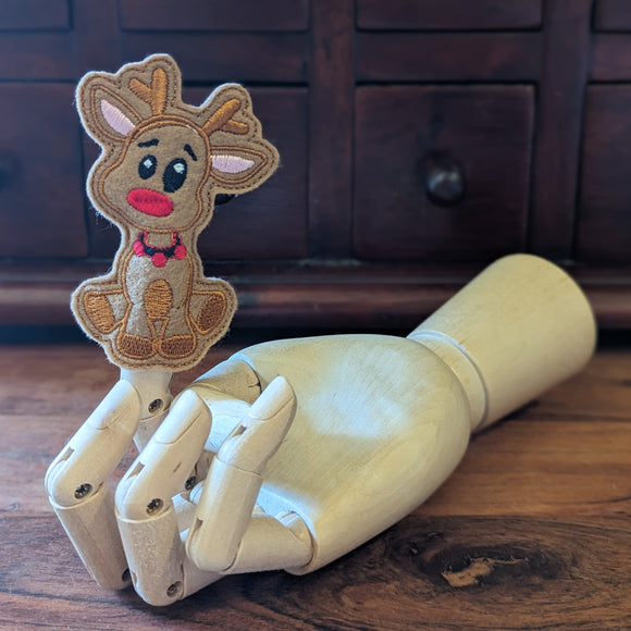 Embroidered rudolph finger puppet made from felt displayed on a wooden mannequin hand. 