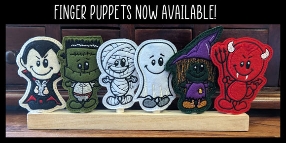 Halloween themed finger puppets in dracula, frankenstein, mummy, ghost, witch and devil designs on wooden display stand.