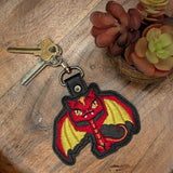Close‑up of embroidered red dragon keychain with yellow wings